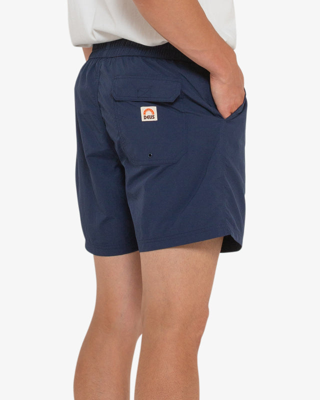navy 16 inch leg elasticated waist board short with back flap pocket, contrast stitching, branded woven label, 95% nylon 5% spandex water resistant fabrication with a garment wash